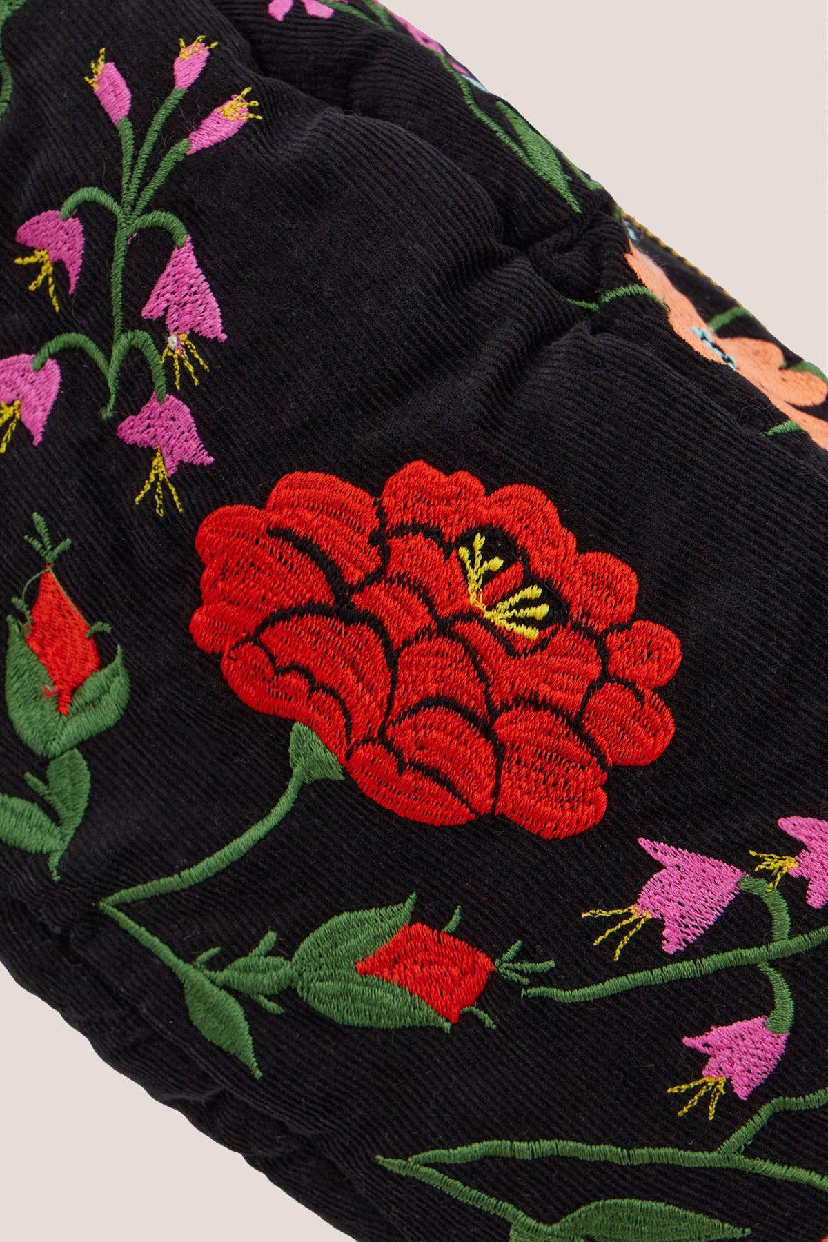 Dettaglio del ricamo sul velluto nero della borsa Ninfa: rosa rossa e campanule rosa
