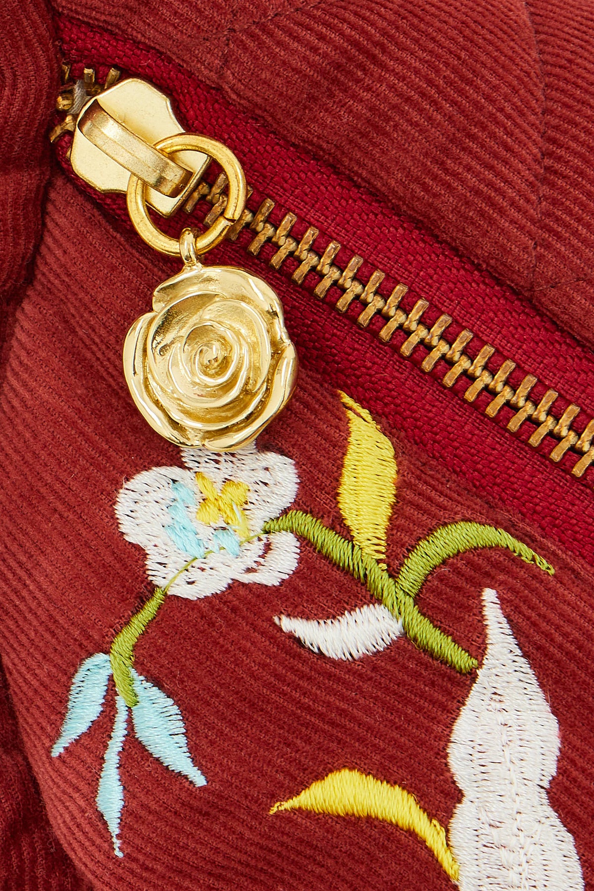 Dettaglio del tirazip a forma di rosa dorata sulla zip della borsa Ninfa Melograno