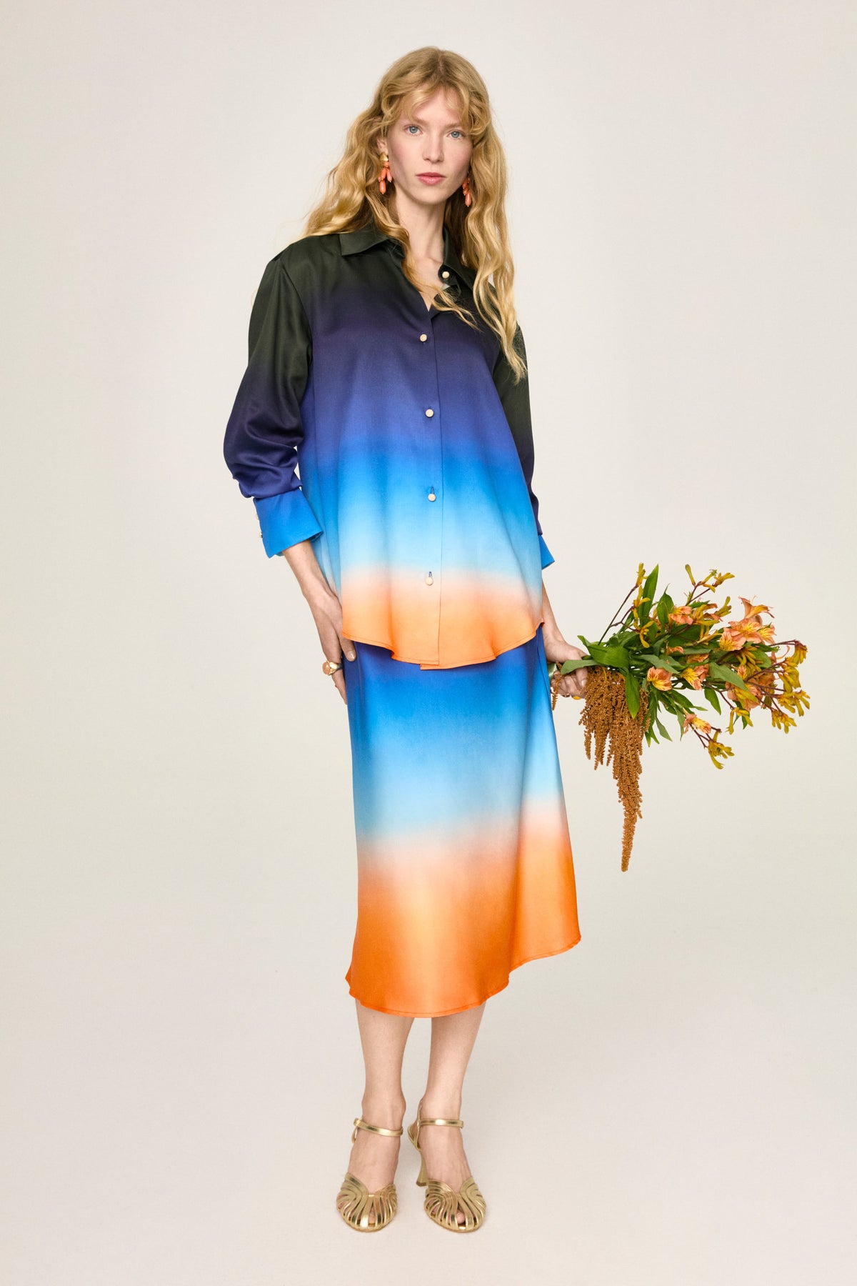 Camicia Luce Aria, figura intera con la gonna Lola e un mazzo di fiori
