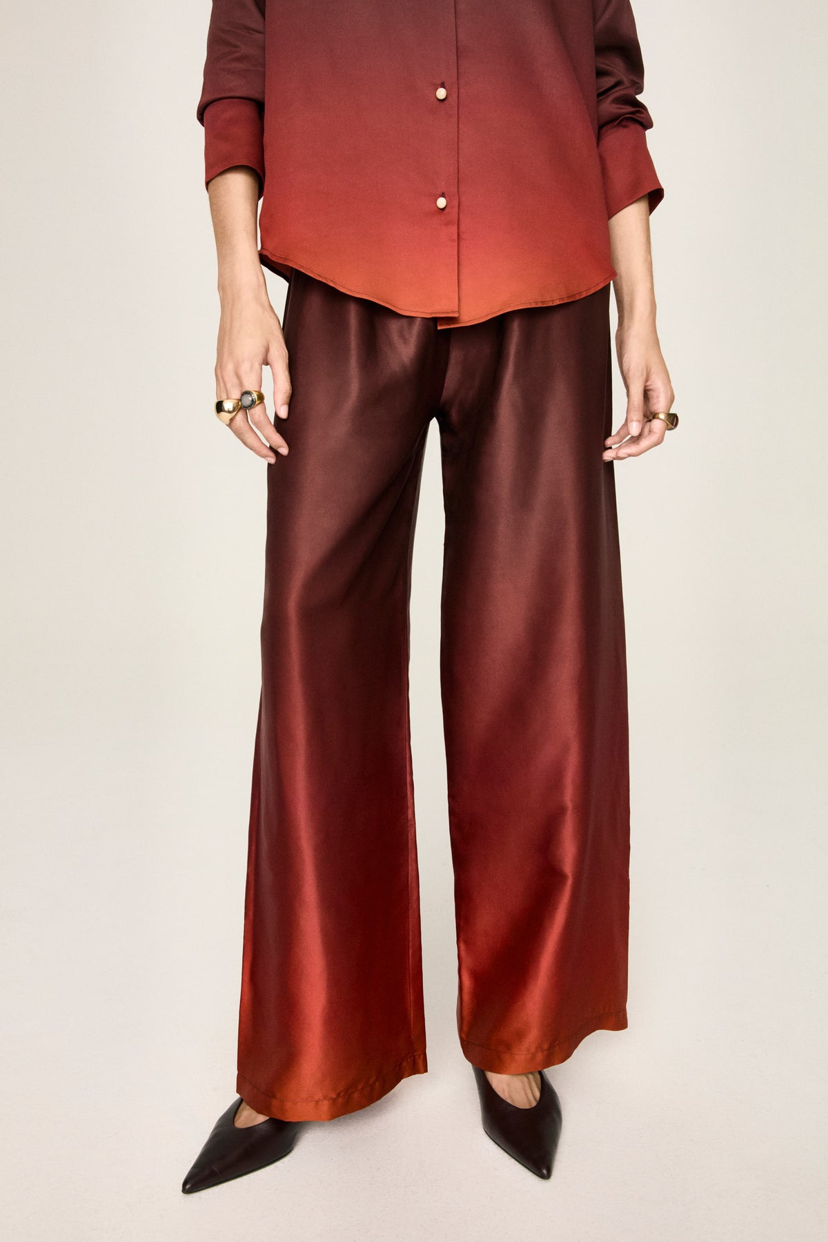 Detail of the gradient print of the Leto Fuoco trousers, from burgundy at the waist to red at the hem